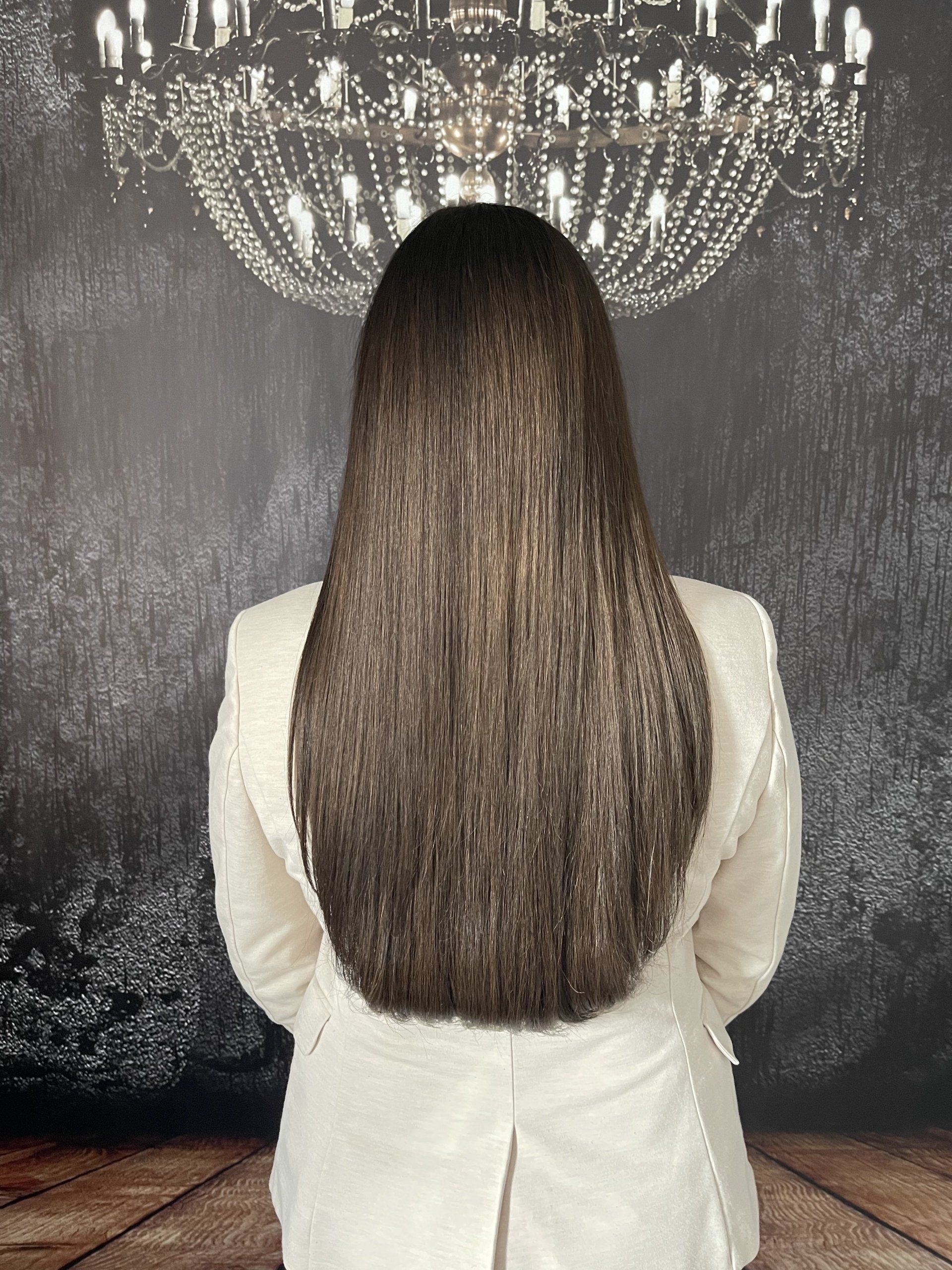 Eine Frau mit langen Haaren steht vor einem Kronleuchter.