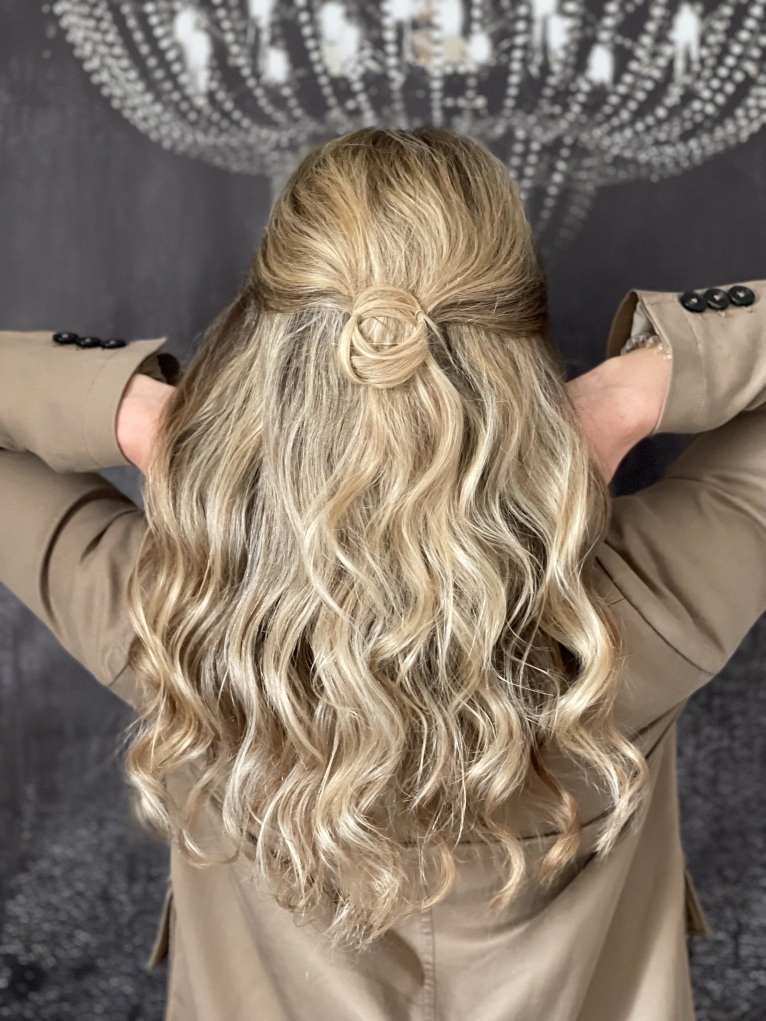 Eine Frau mit langen blonden Haaren trägt eine halb hochgesteckte, halb offene Frisur.