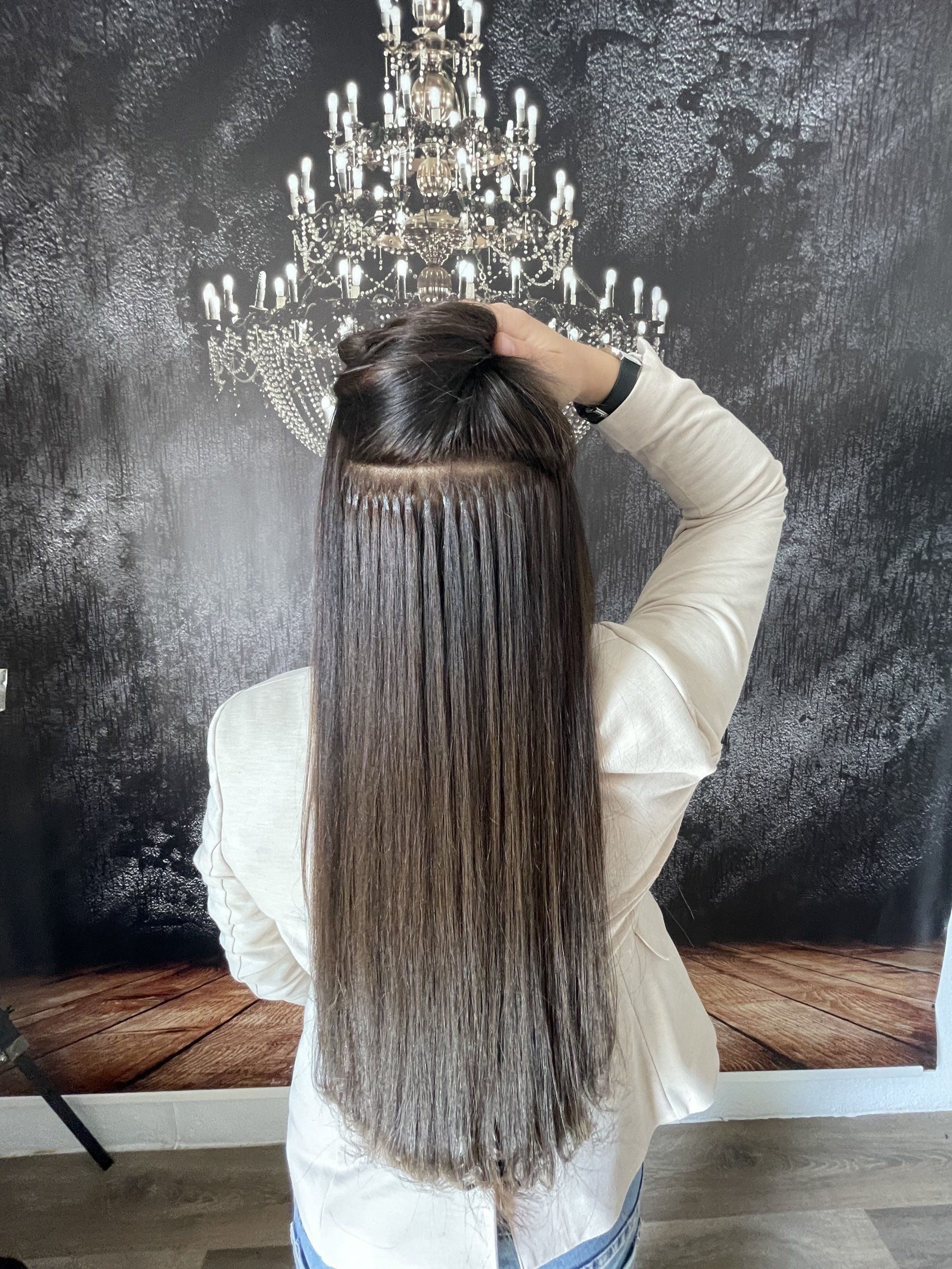 Eine Frau mit langen Haaren steht vor einem Kronleuchter.