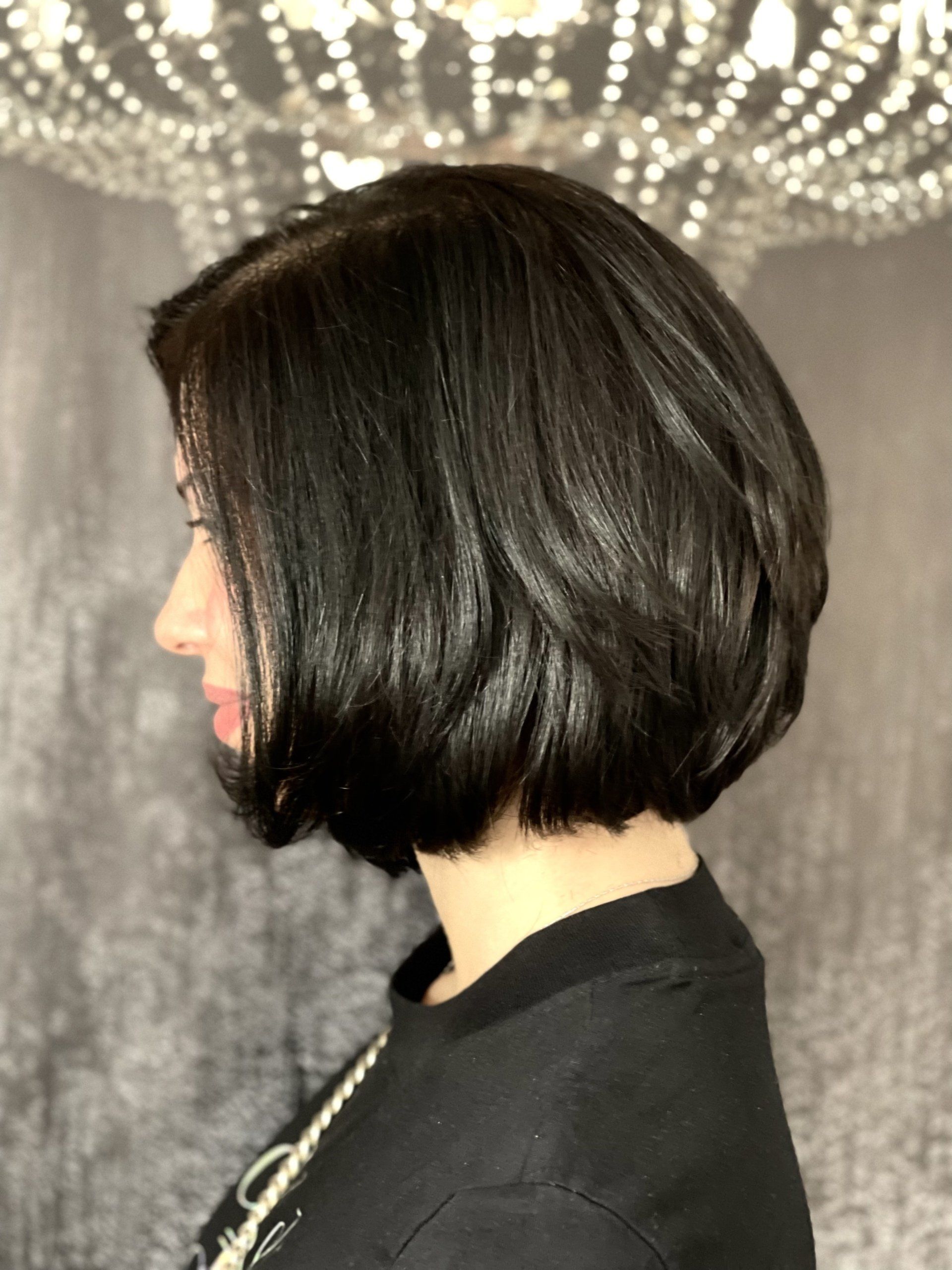 Eine Frau mit kurzen schwarzen Haaren steht vor einem Kronleuchter.