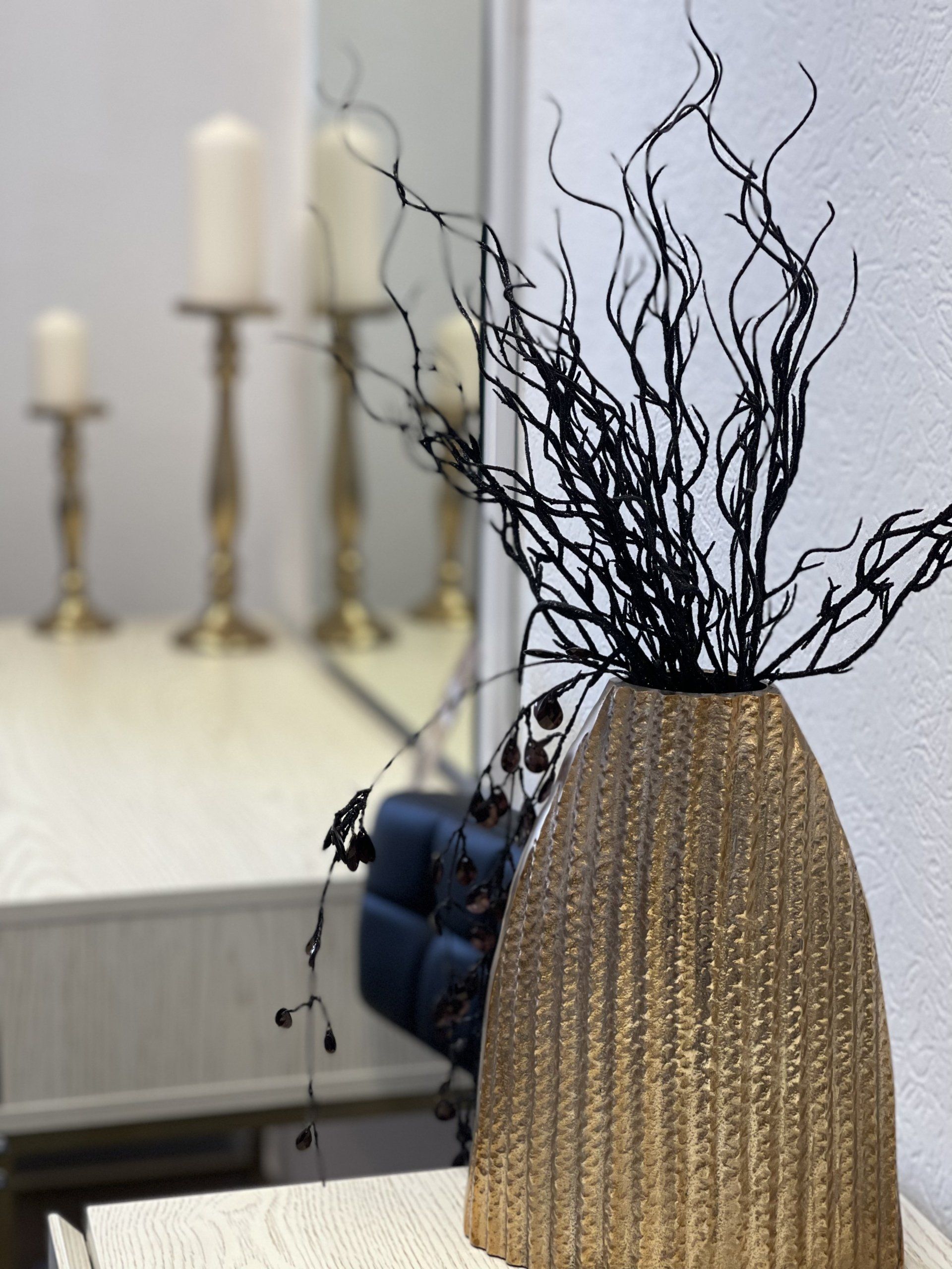 Eine goldene Vase mit schwarzen Zweigen darin