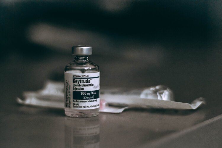 A bottle of injection is sitting on a table next to a syringe.