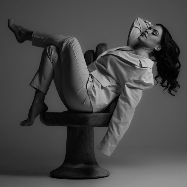 A person in a light-colored suit reclining on a sculptural.