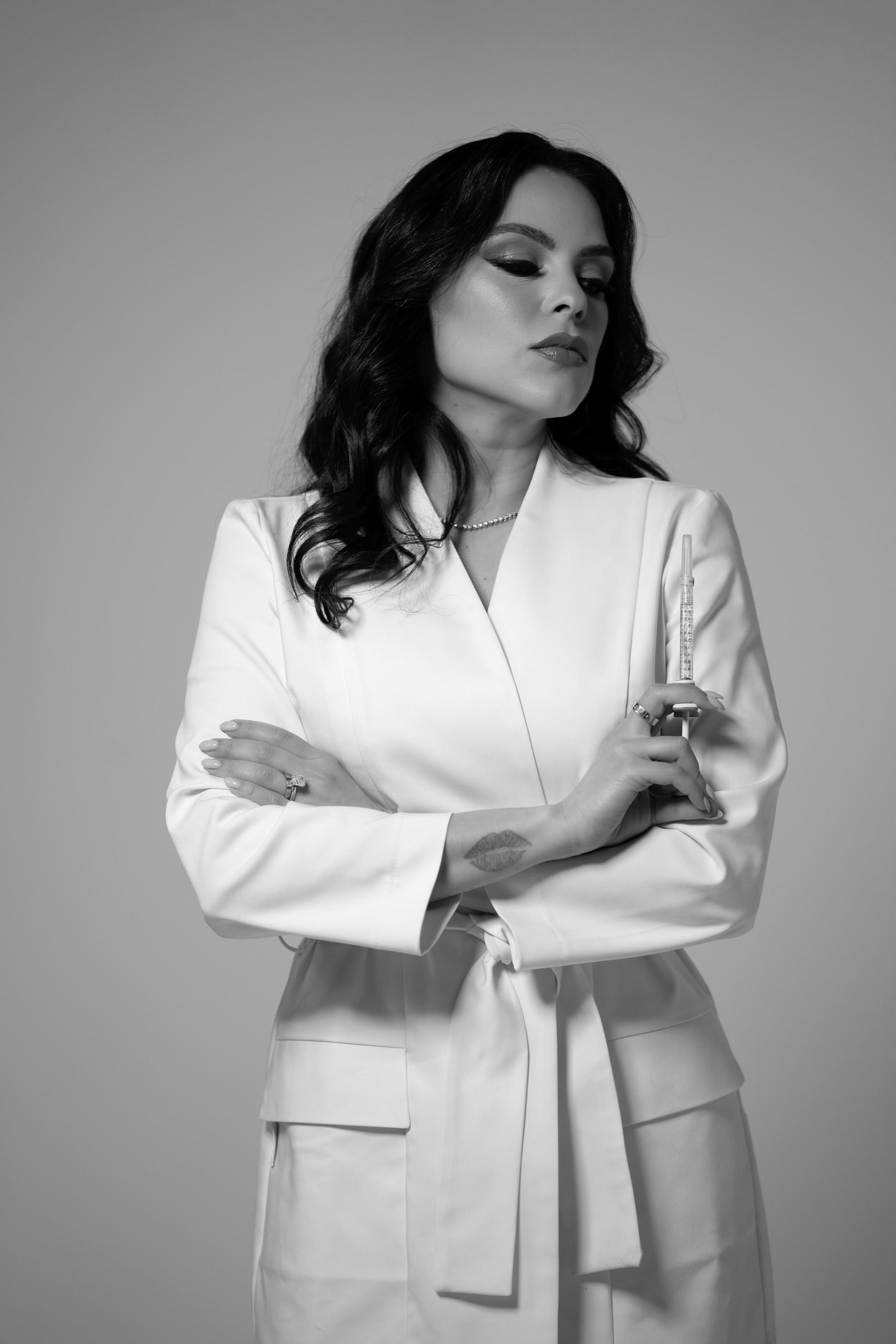 Dr Kaly Castellanos with a white lab coat stands with arms crossed