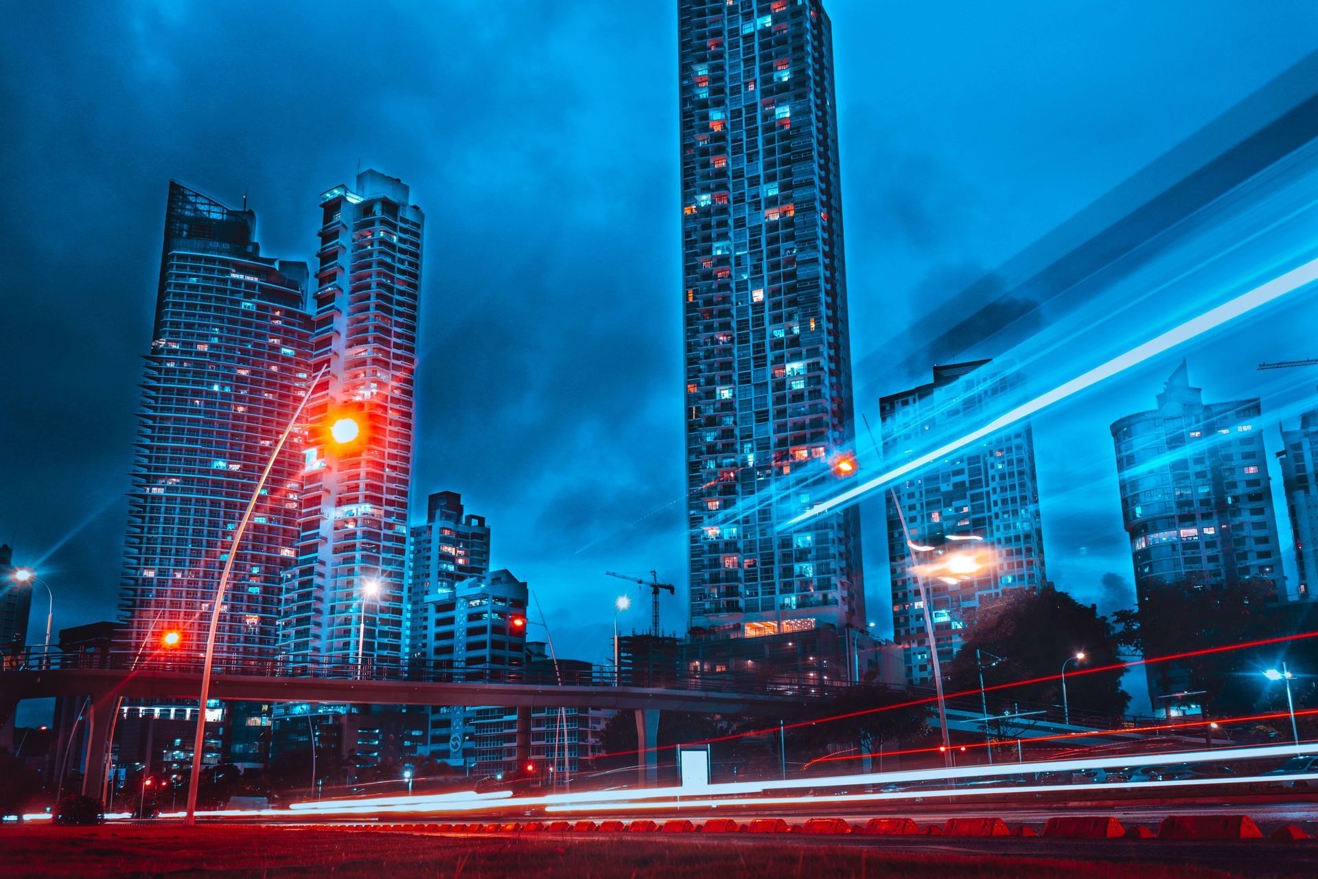 City skyline at dusk; long exposure captures streaks of car lights and glowing buildings.