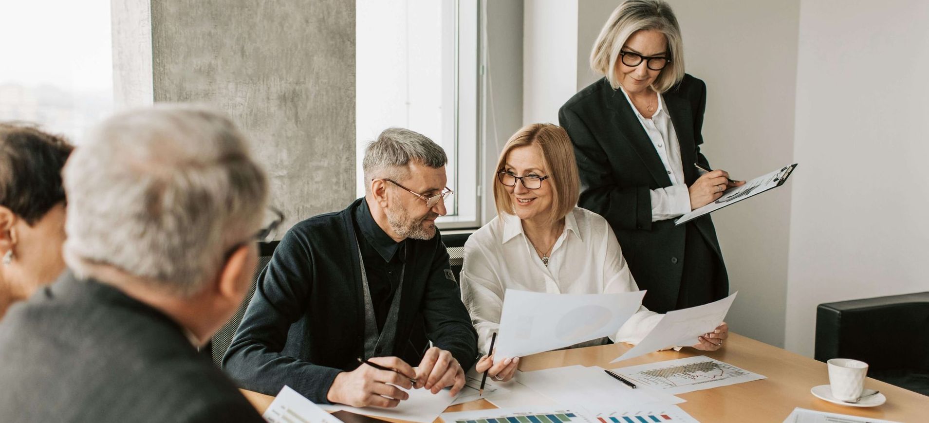 Group of people in business attire at a meeting, reviewing documents.