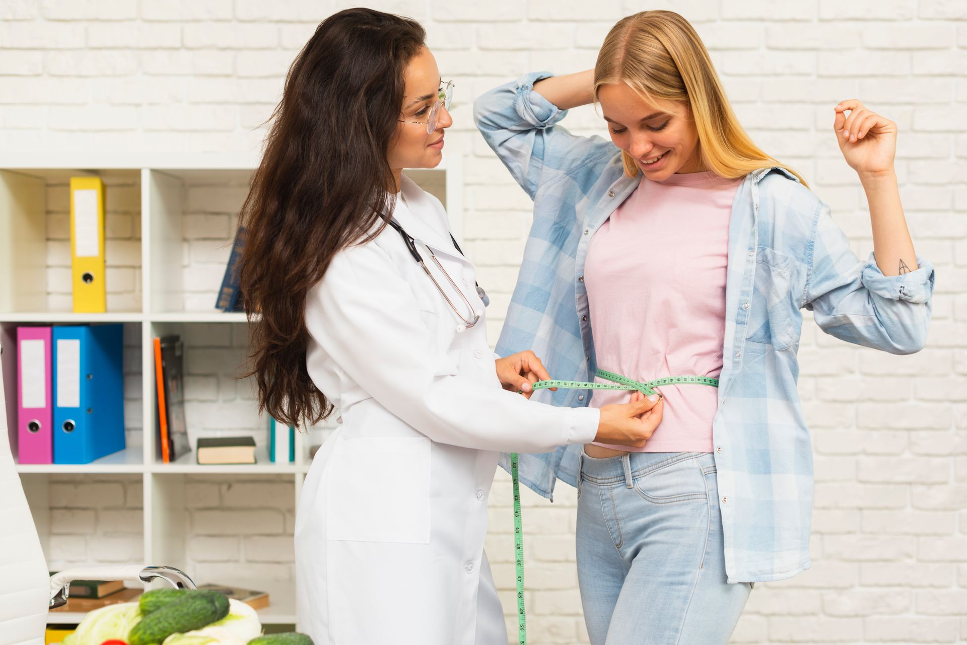 Dietitian measuring waist of a patient in office setting.