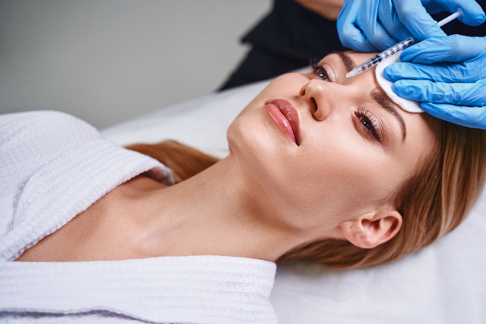 a woman is getting a botox injection in her face .