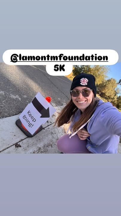 A woman smiles, holding a sign that says 