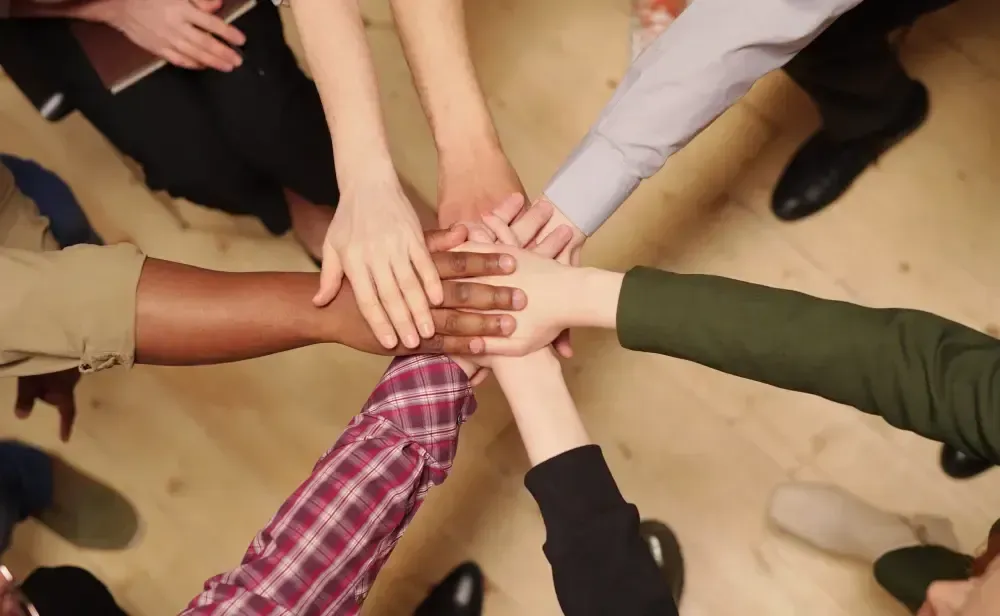 A group of people are putting their hands together in a circle.