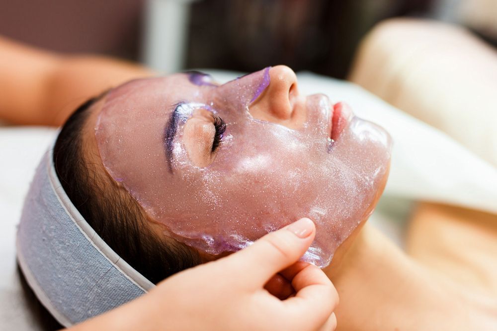 Woman receiving a facial massage with a white cream mask and headband