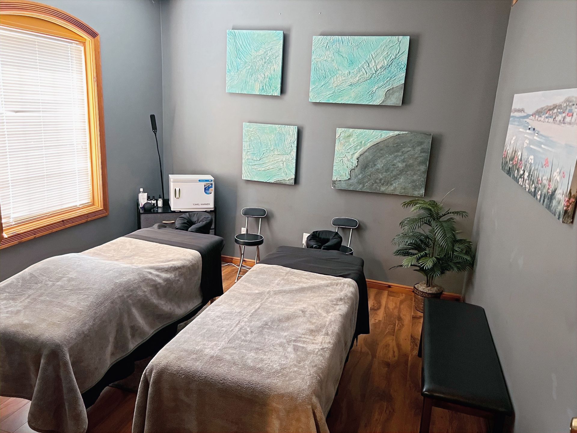 A room with two massage tables and paintings on the wall.