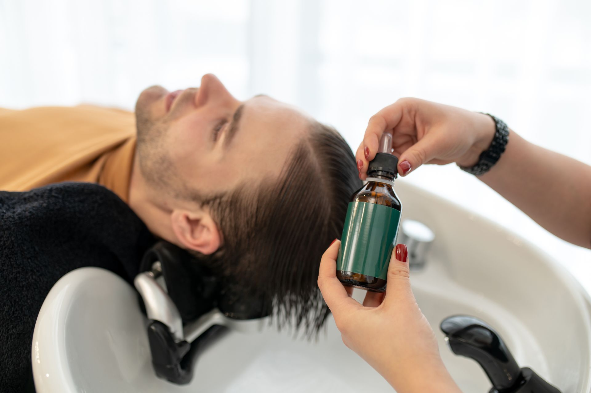 A man is getting his hair washed in a sink at a hair salon.