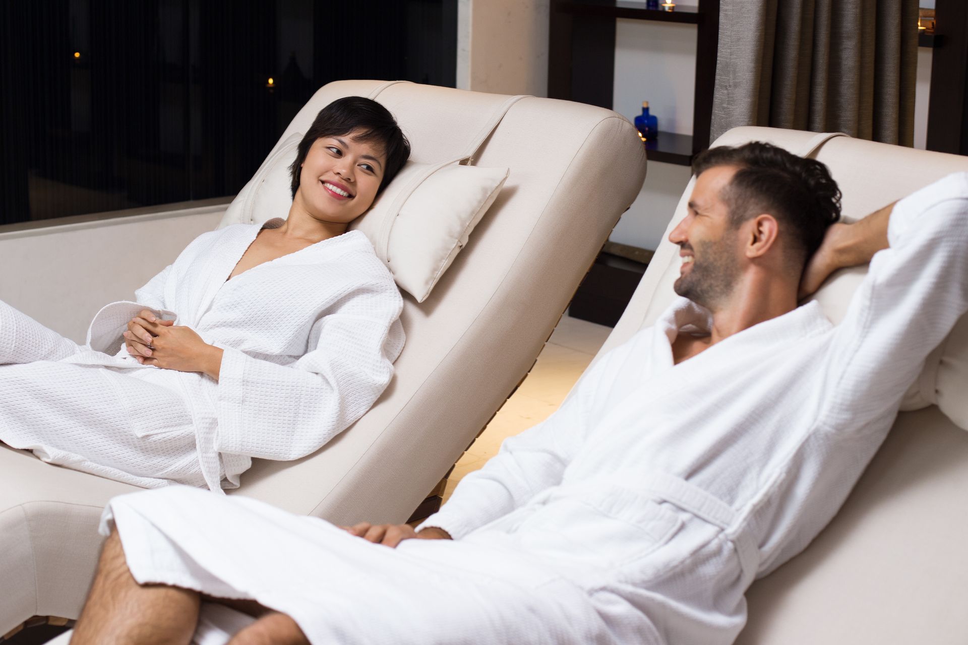 A man and a woman are laying in lounge chairs at a spa.