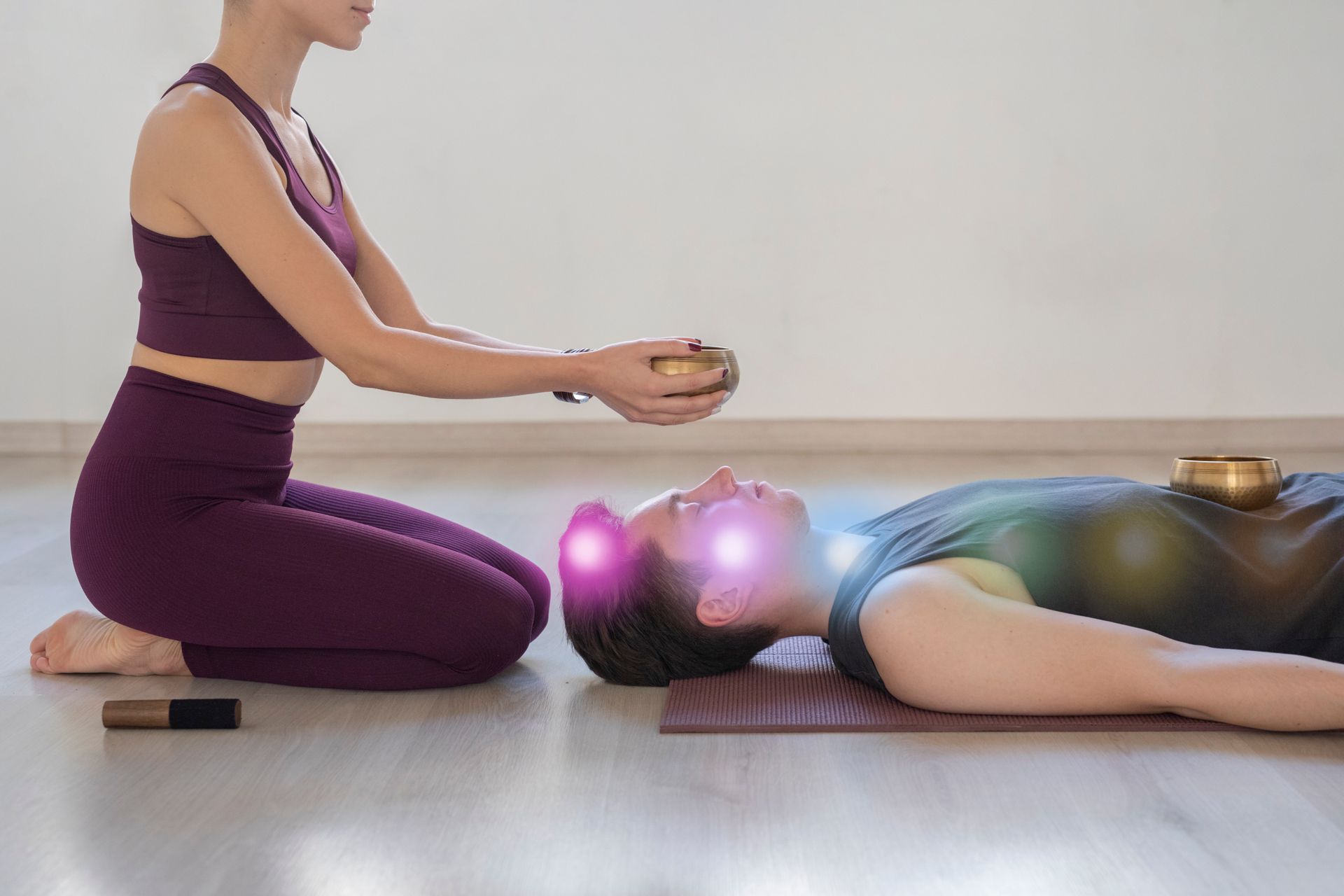 Woman holding a singing bowl over a person lying down, with glowing lights indicating energy points.