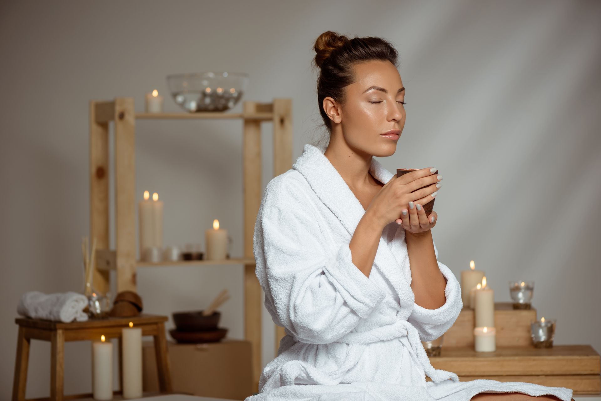 A woman in a bathrobe is drinking a cup of coffee in a spa.