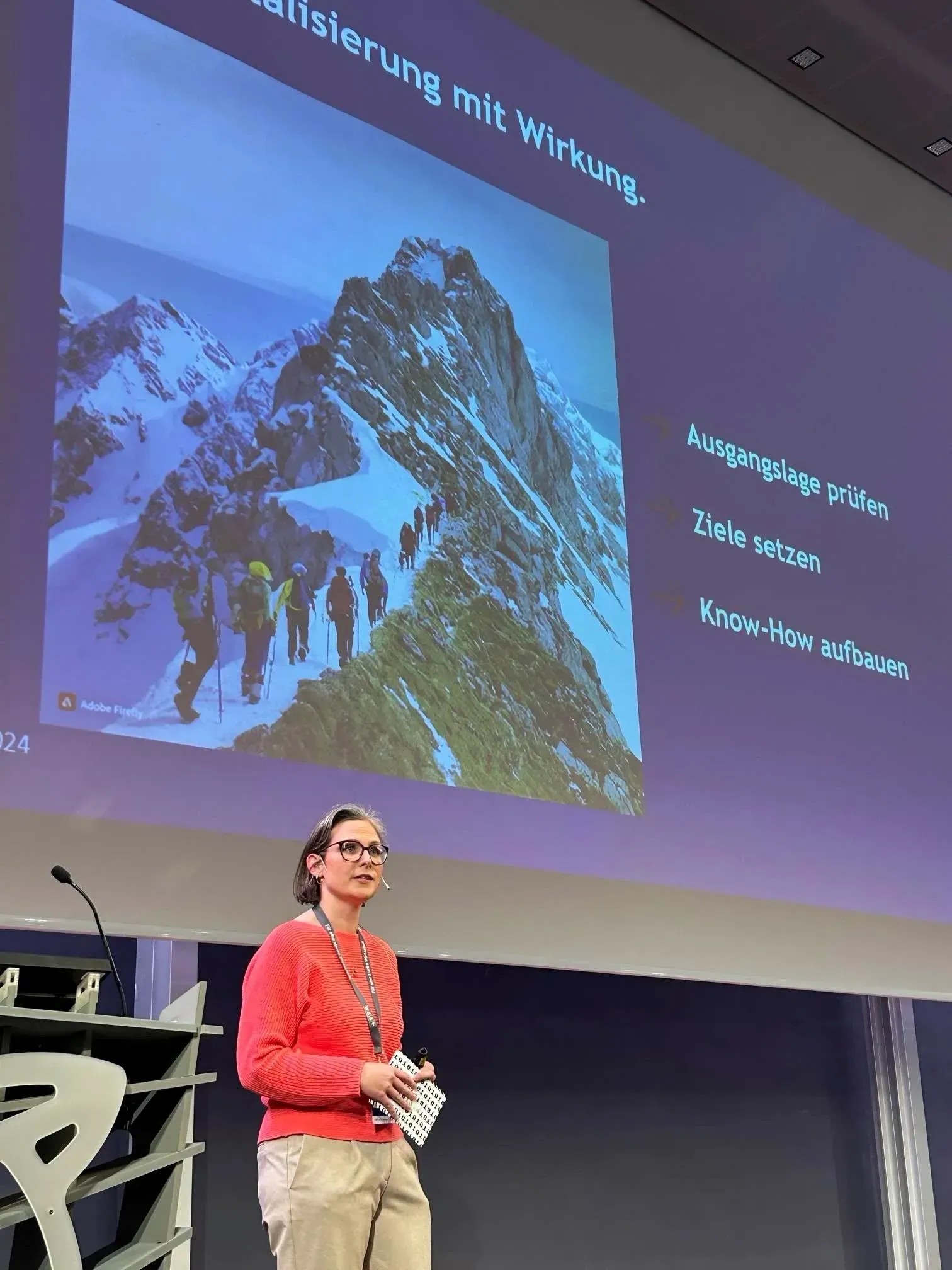 Eine Frau steht auf einer Bühne und präsentiert auf einer Konferenz Salzburg eDay 2024.