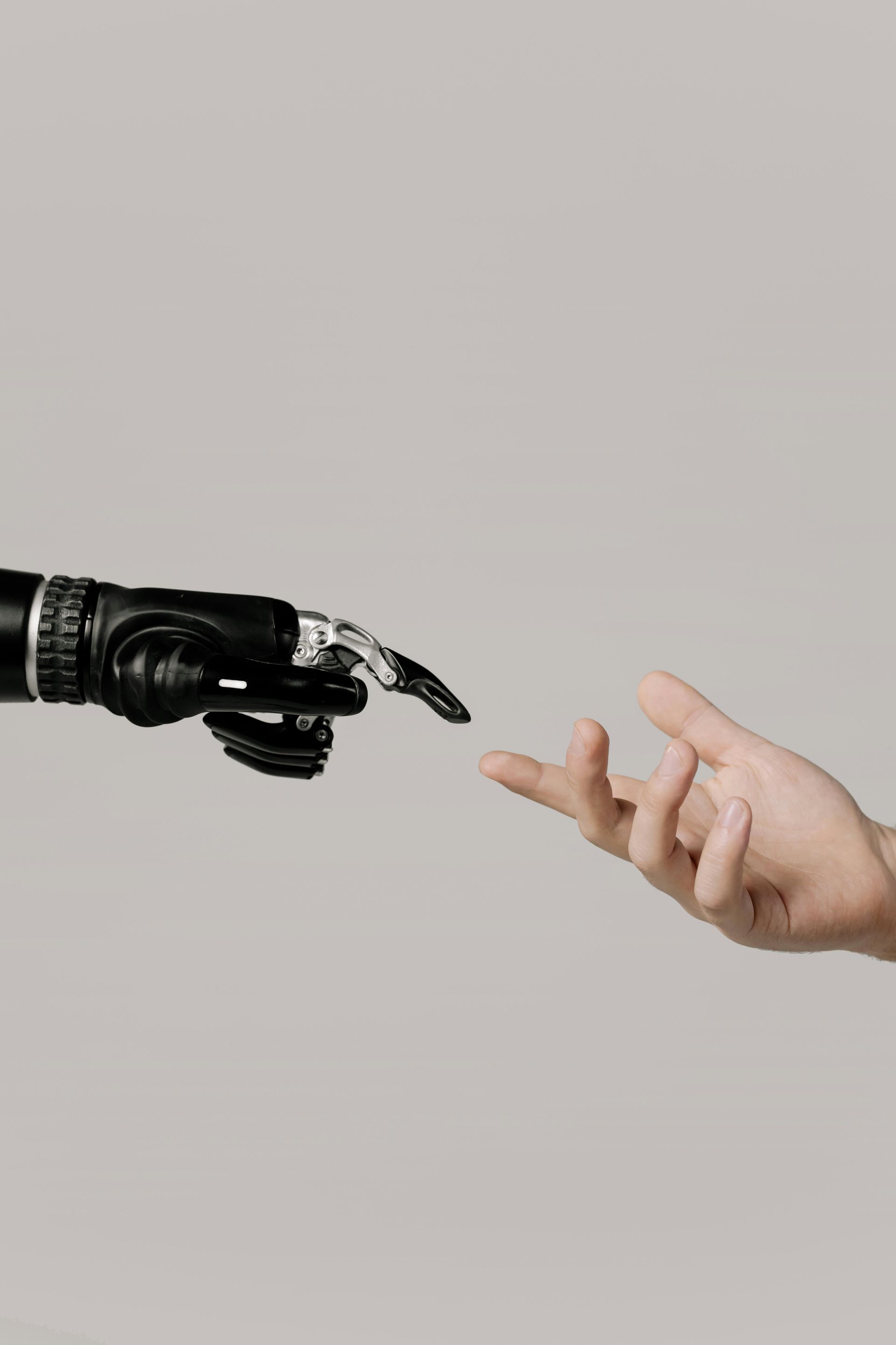 Roboterhand und menschliche Hand berühren sich fast vor einem grauen Hintergrund.