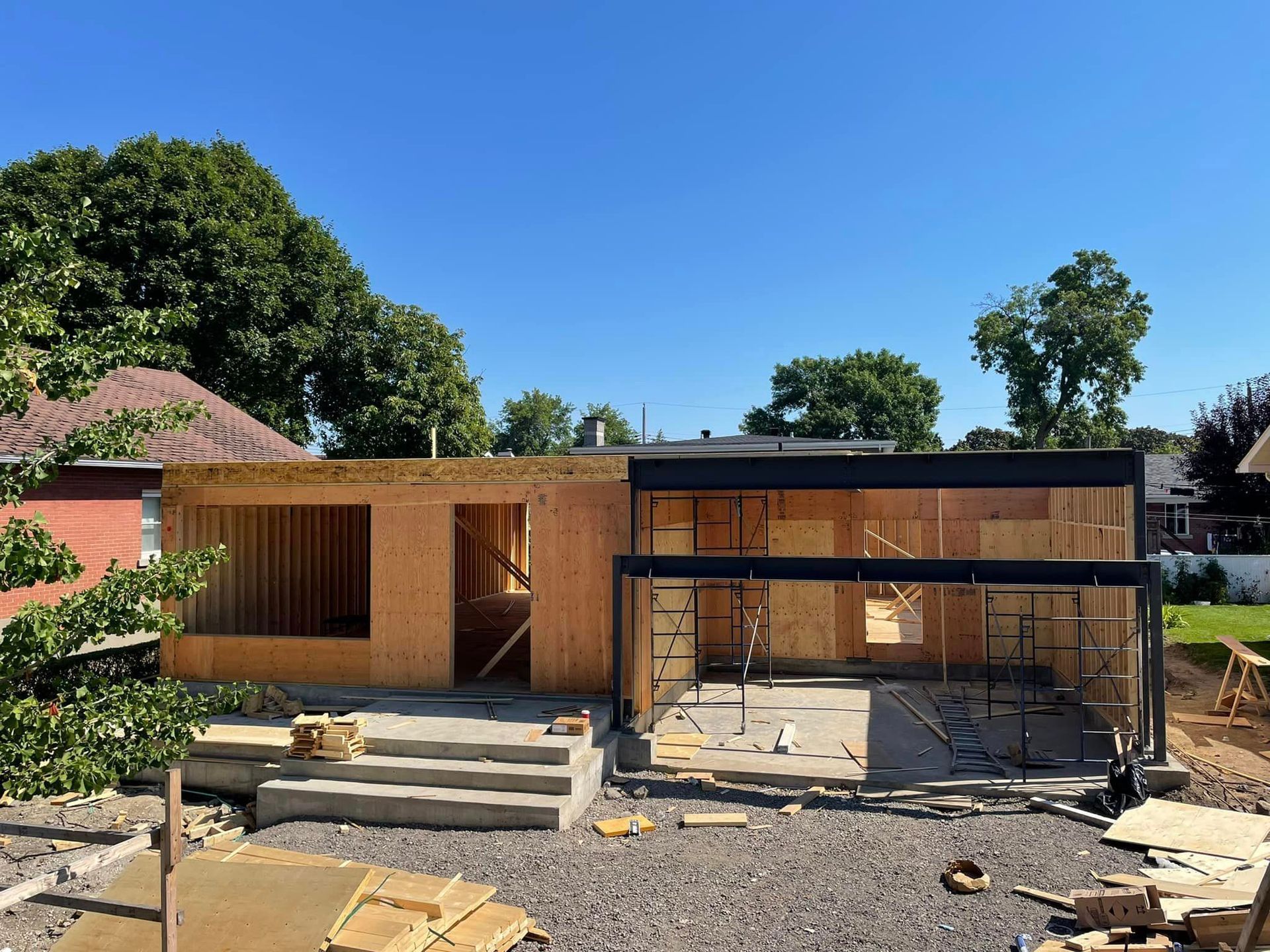 Une maison est en construction sur un terrain en gravier avec un ciel bleu en arrière-plan.