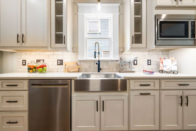 Bright kitchen with white cabinets, stainless steel appliances, and a farmhouse sink under a window.