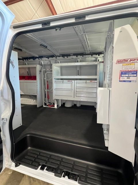 Open van interior with custom white storage cabinets and black floor lining