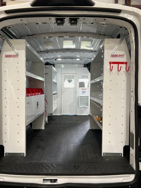Interior of a white cargo van with built-in storage shelves and cabinets in the rear.