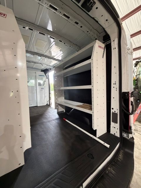 Inside a white cargo van, showing built-in shelving and a black floor cargo area.