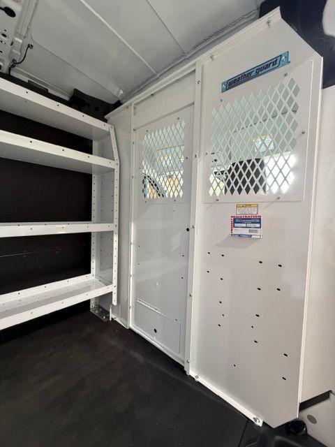 White van interior with metal cargo shelves and a mesh partition door at the rear