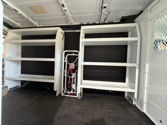 Interior of a van with built-in white shelving units and a central power/electrical panel.
