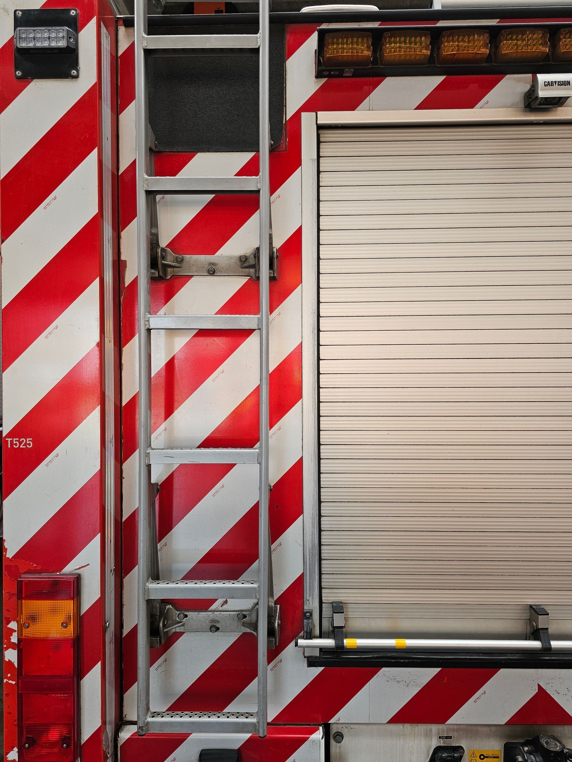 Fire truck side with red-and-white chevrons and a closed roll-up compartment door
