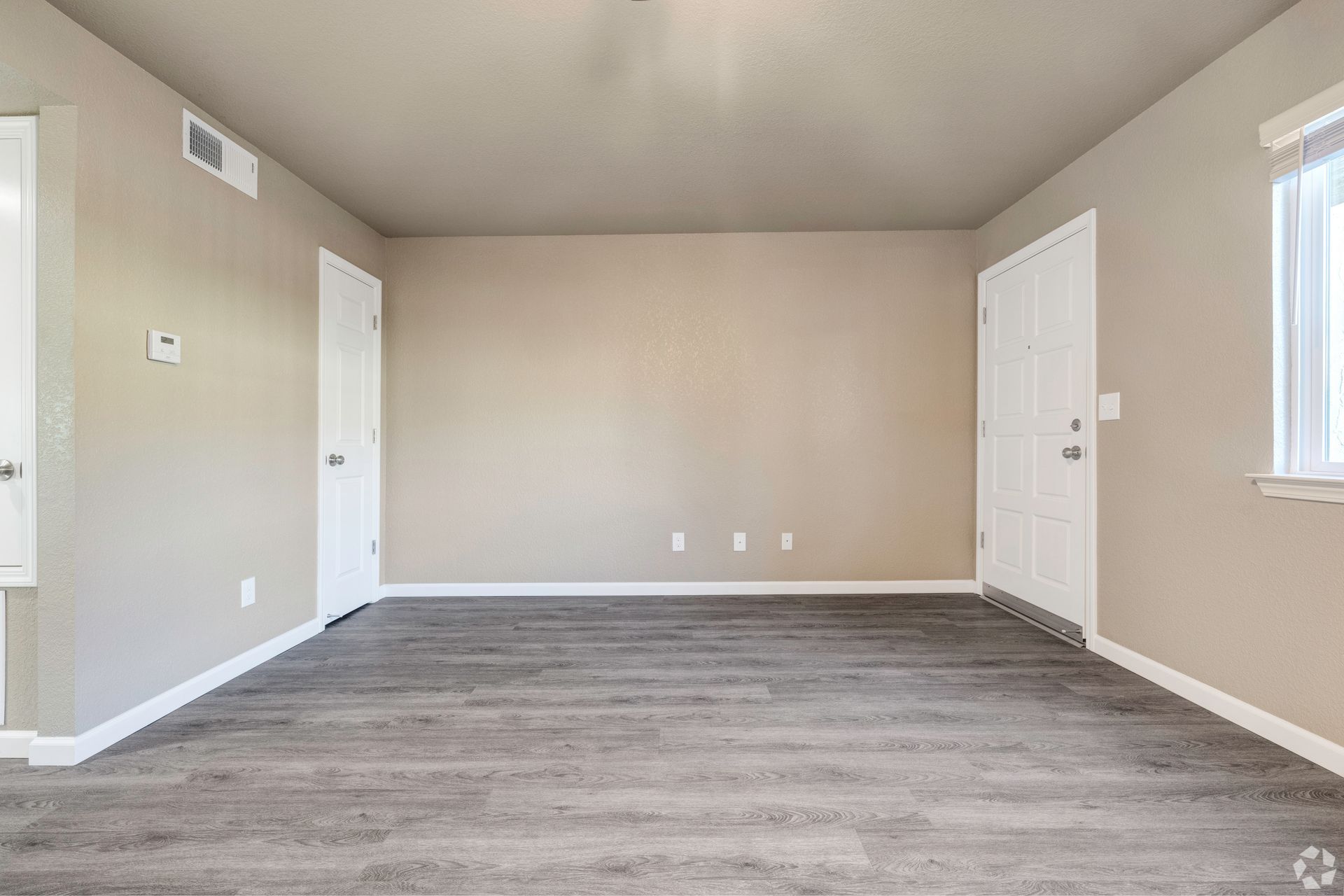 Empty room with gray flooring, beige walls, white doors and trim, and a window.