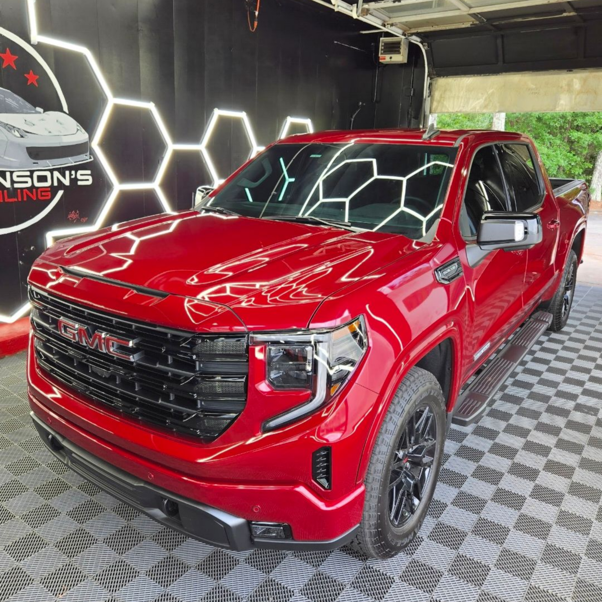 Red GMC pickup truck in a showroom with a black and white checkered floor.