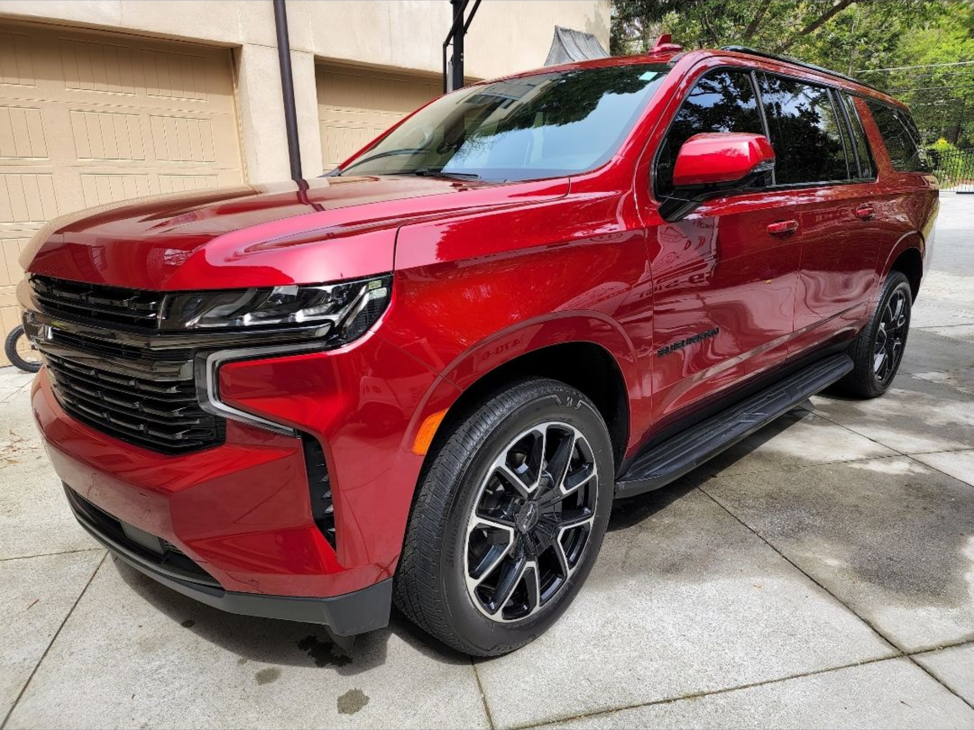 Red SUV parked in a driveway beside a beige house