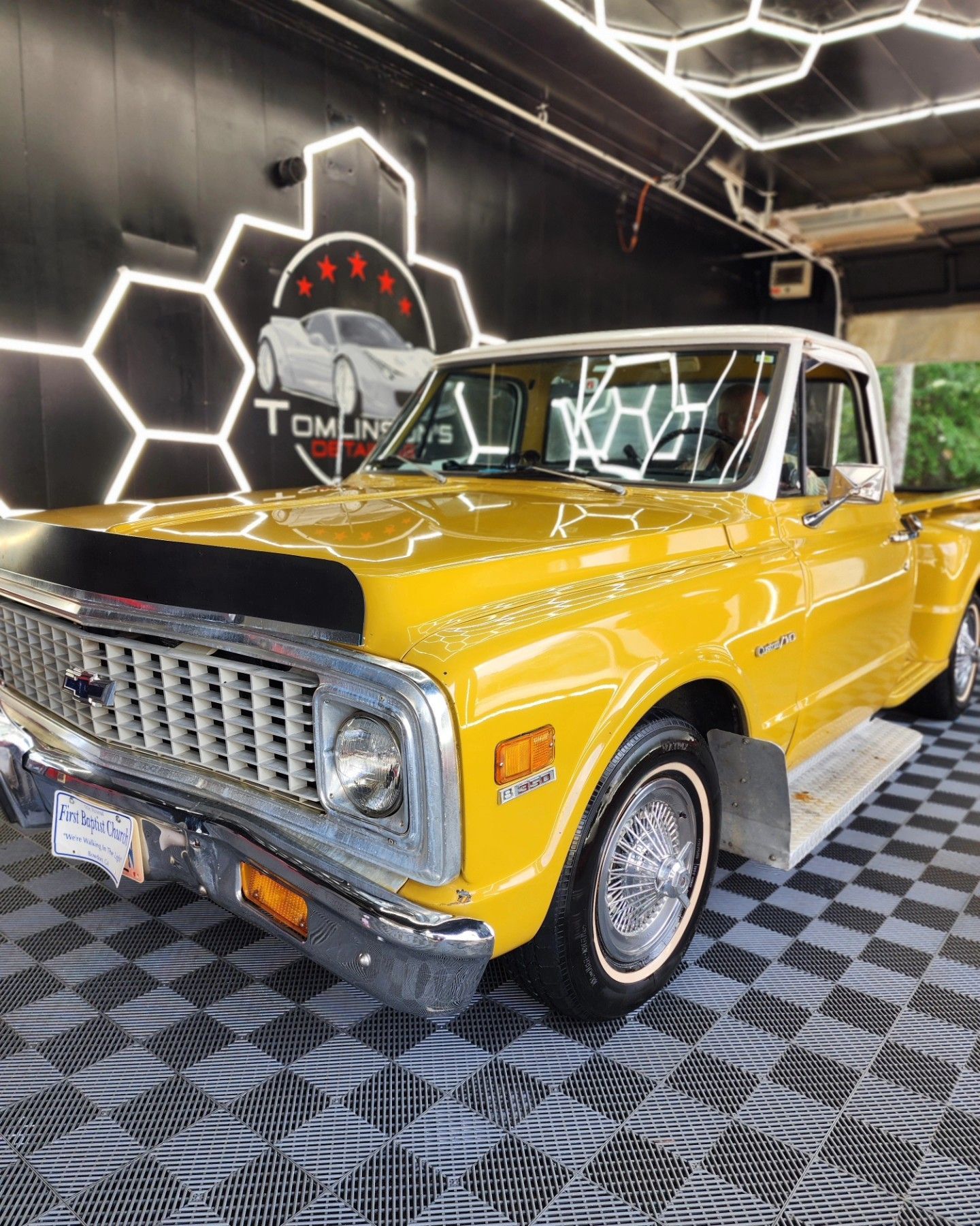 Yellow and white vintage Chevrolet pickup truck on a tiled floor, under bright lights.