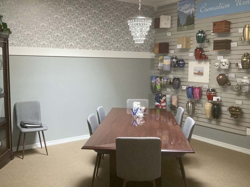 Small showroom with a wooden conference table, gray chairs, and wall-mounted decorative items.