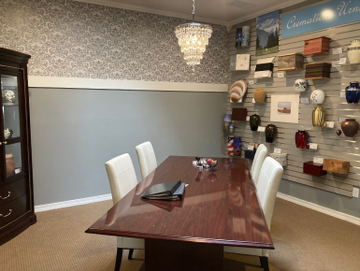 Dining room with dark wood table, white chairs, chandelier, and decorative wall shelves.