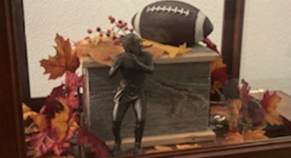 Fall-themed tabletop display with a wooden box, autumn leaves, and a small football decoration