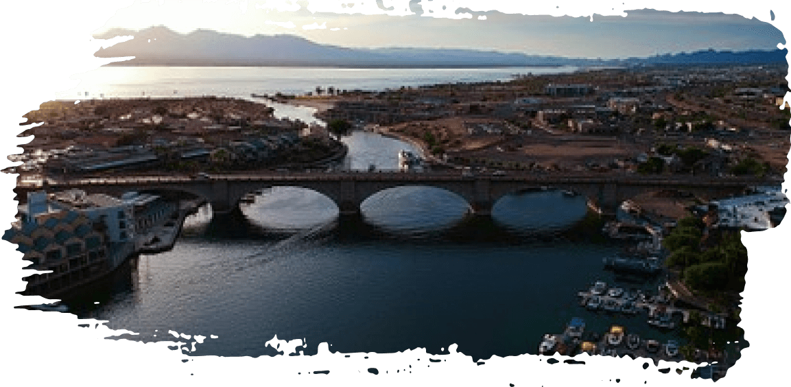 Aerial view of a stone bridge over a river at sunset, with buildings along the waterfront