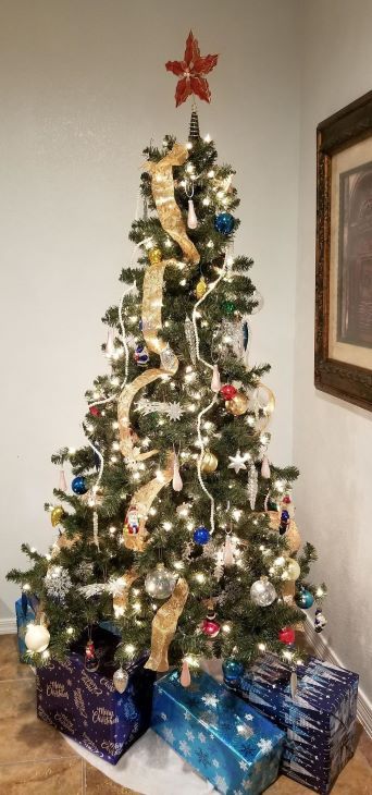 Decorated Christmas tree with lights, ornaments, and wrapped gifts at the base
