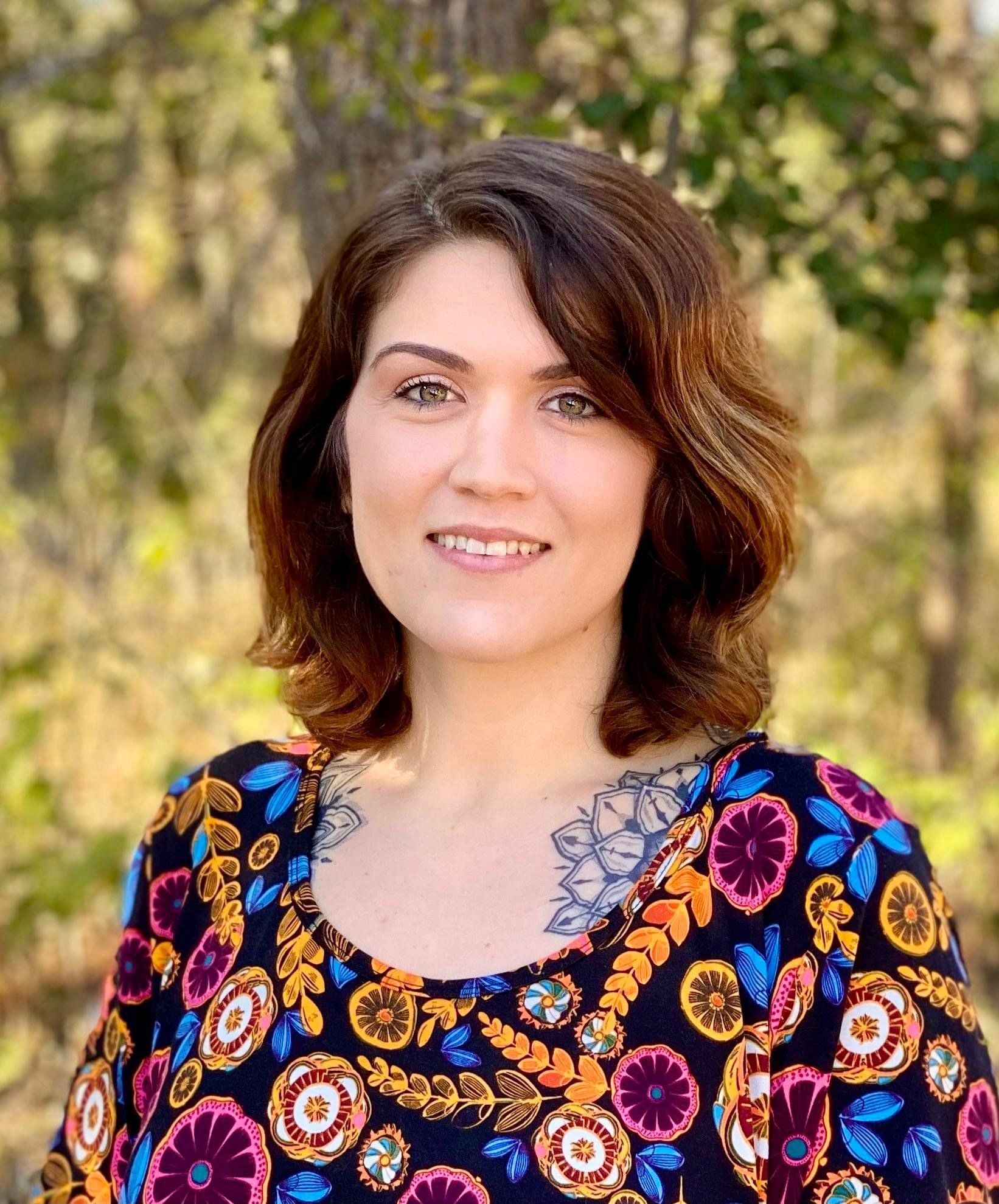 A woman in a colorful floral shirt is smiling for the camera. A woman in a colorful floral shirt is smiling for the camera.