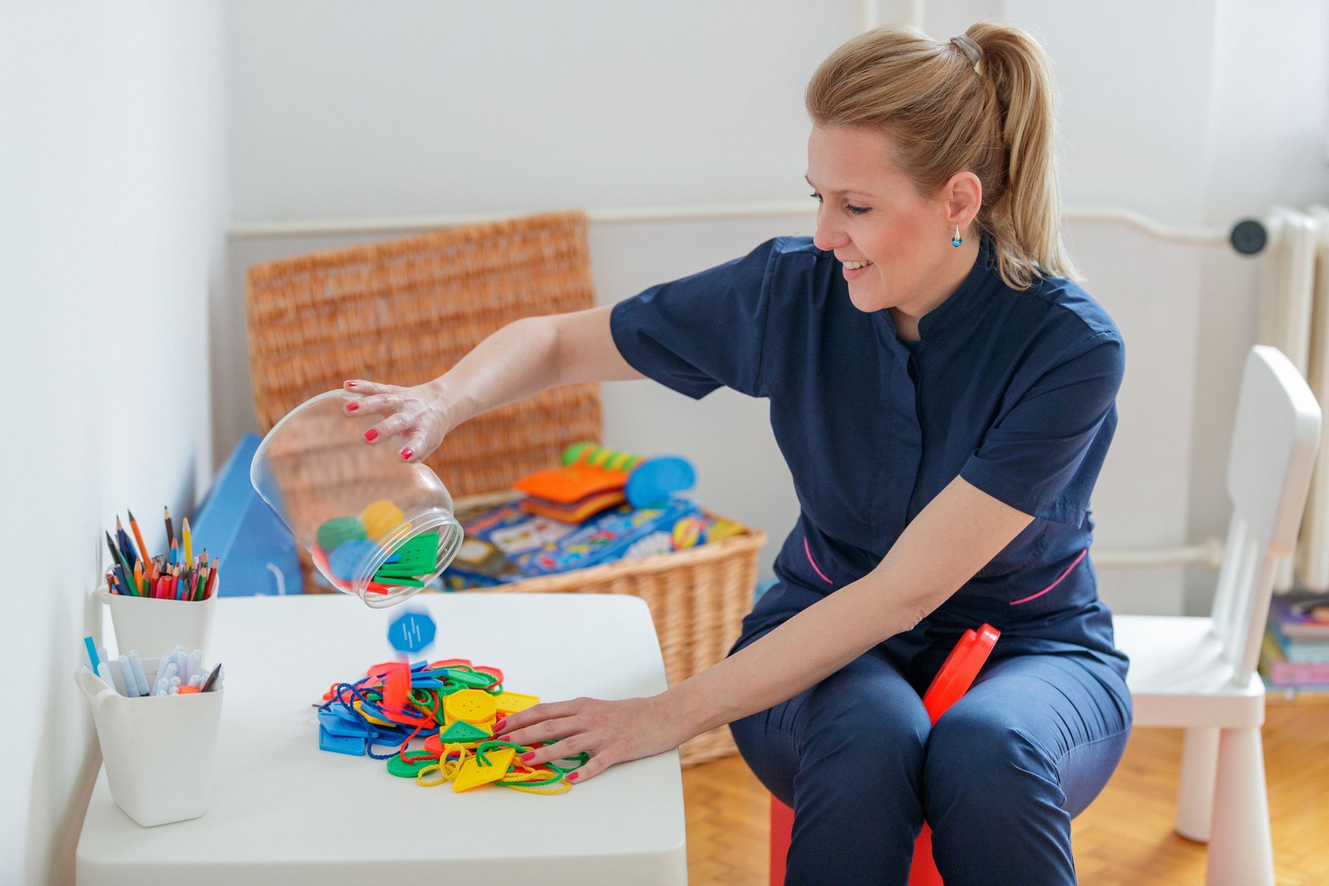 A woman is sitting at a table playing with toys. A woman is sitting at a table playing with toys.