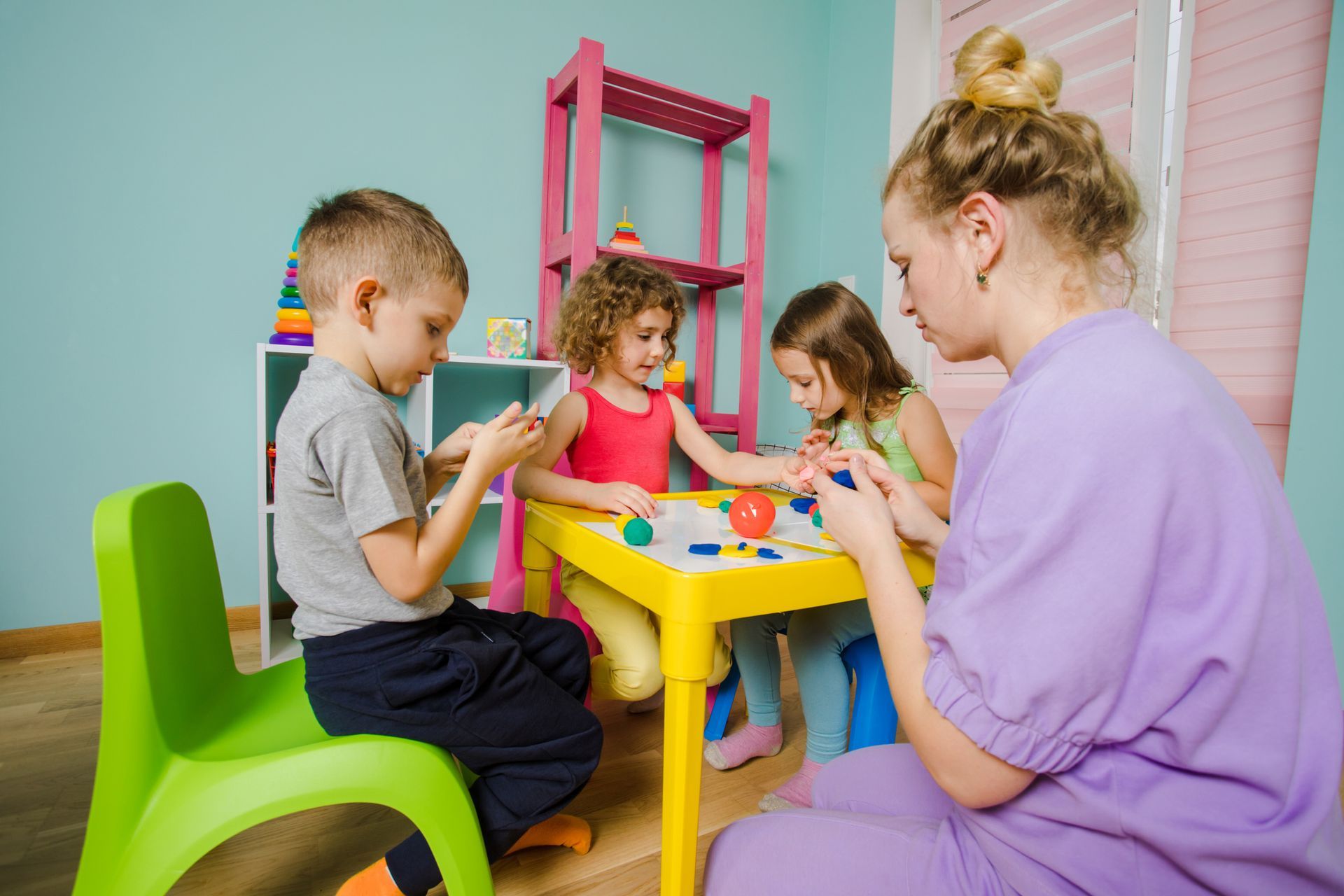 A woman is sitting at a table with three children. A woman is sitting at a table with three children.