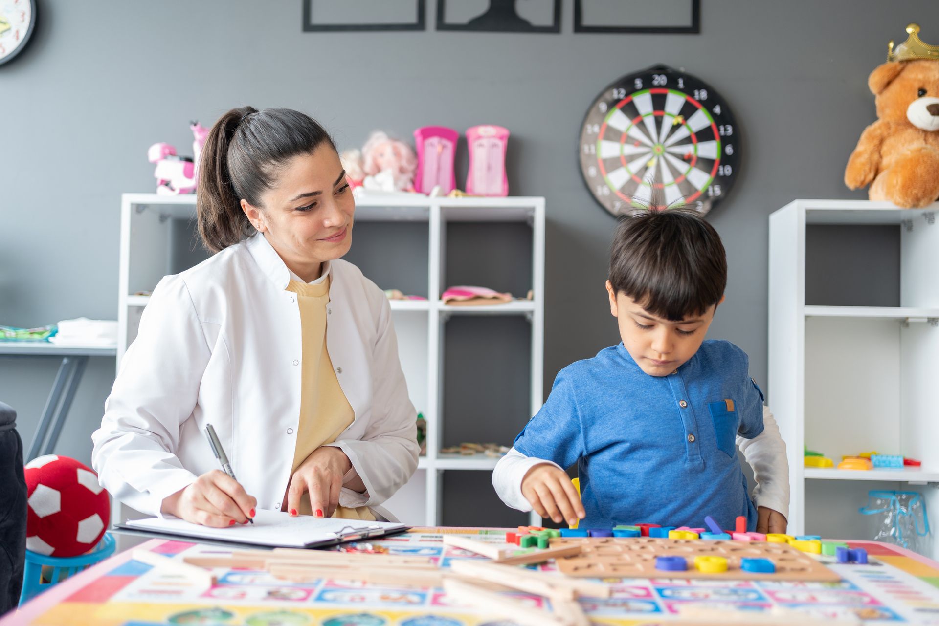 A woman is sitting at a table with a child playing with blocks. A woman is sitting at a table with a child playing with blocks.