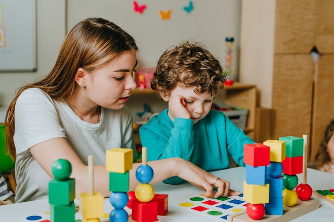 A girl and a boy are playing with blocks at a table. A girl and a boy are playing with blocks at a table.