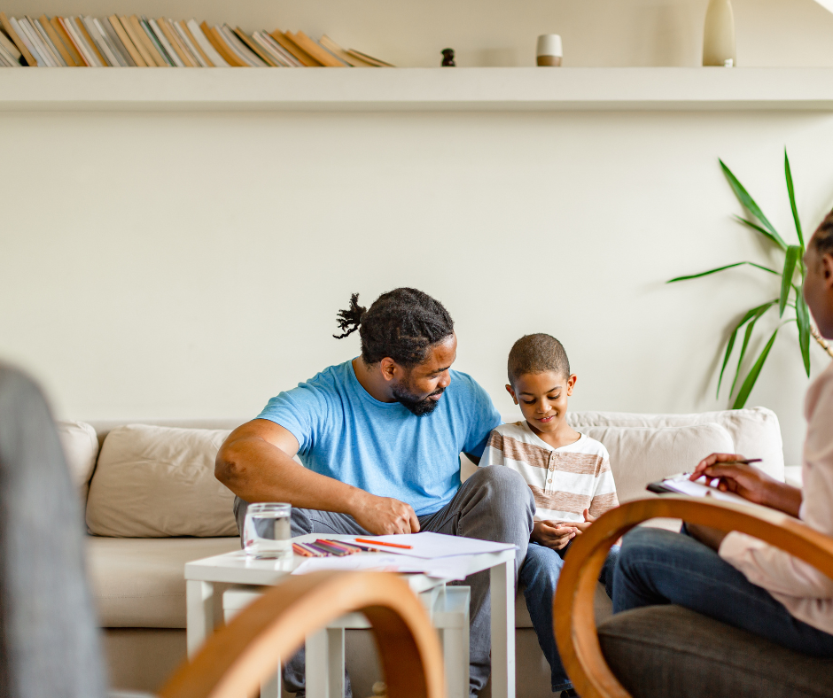 A man and a child are sitting on a couch talking to a woman.