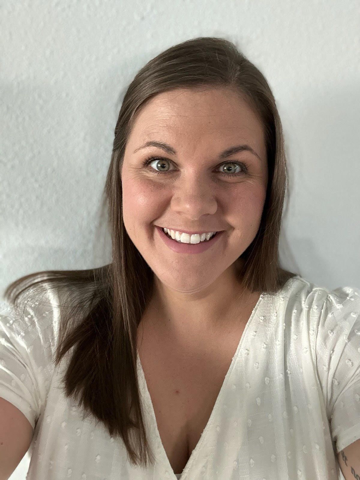 A woman in a white shirt is smiling for the camera. A woman in a white shirt is smiling for the camera.