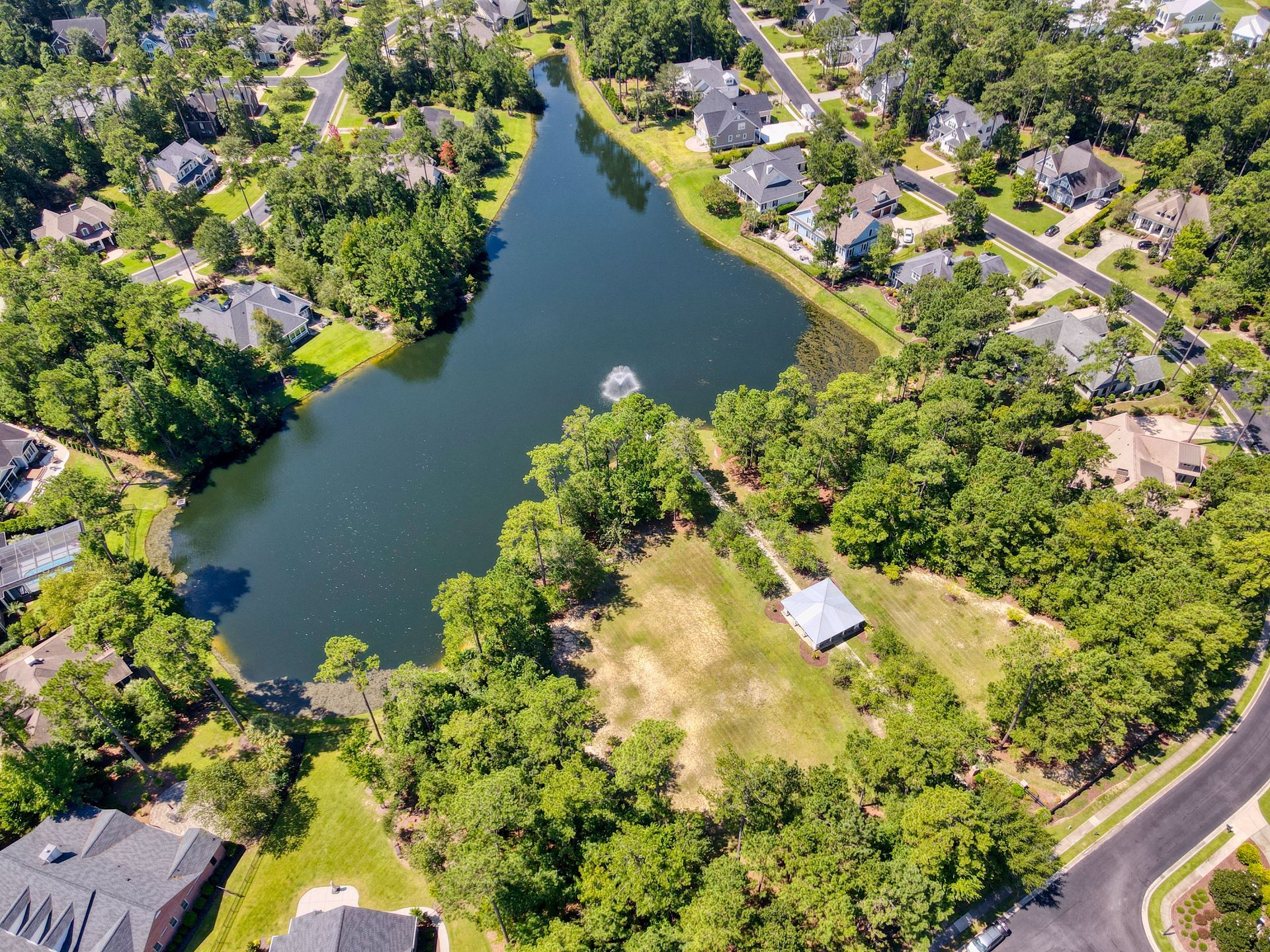 Aerial view of a lake surrounded by trees and residential houses.