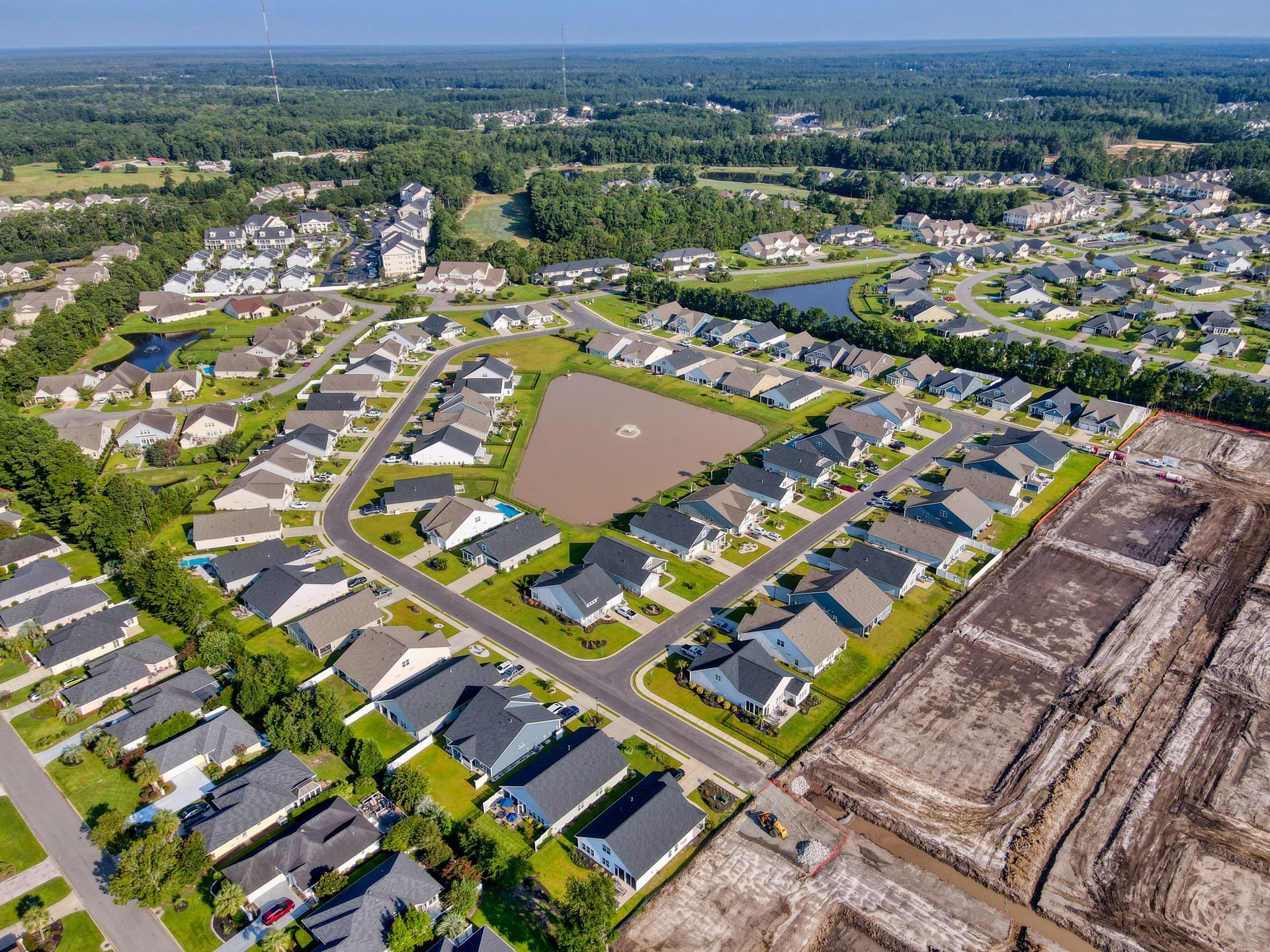 Aerial view of a suburban neighborhood with houses, streets, and an undeveloped lot.