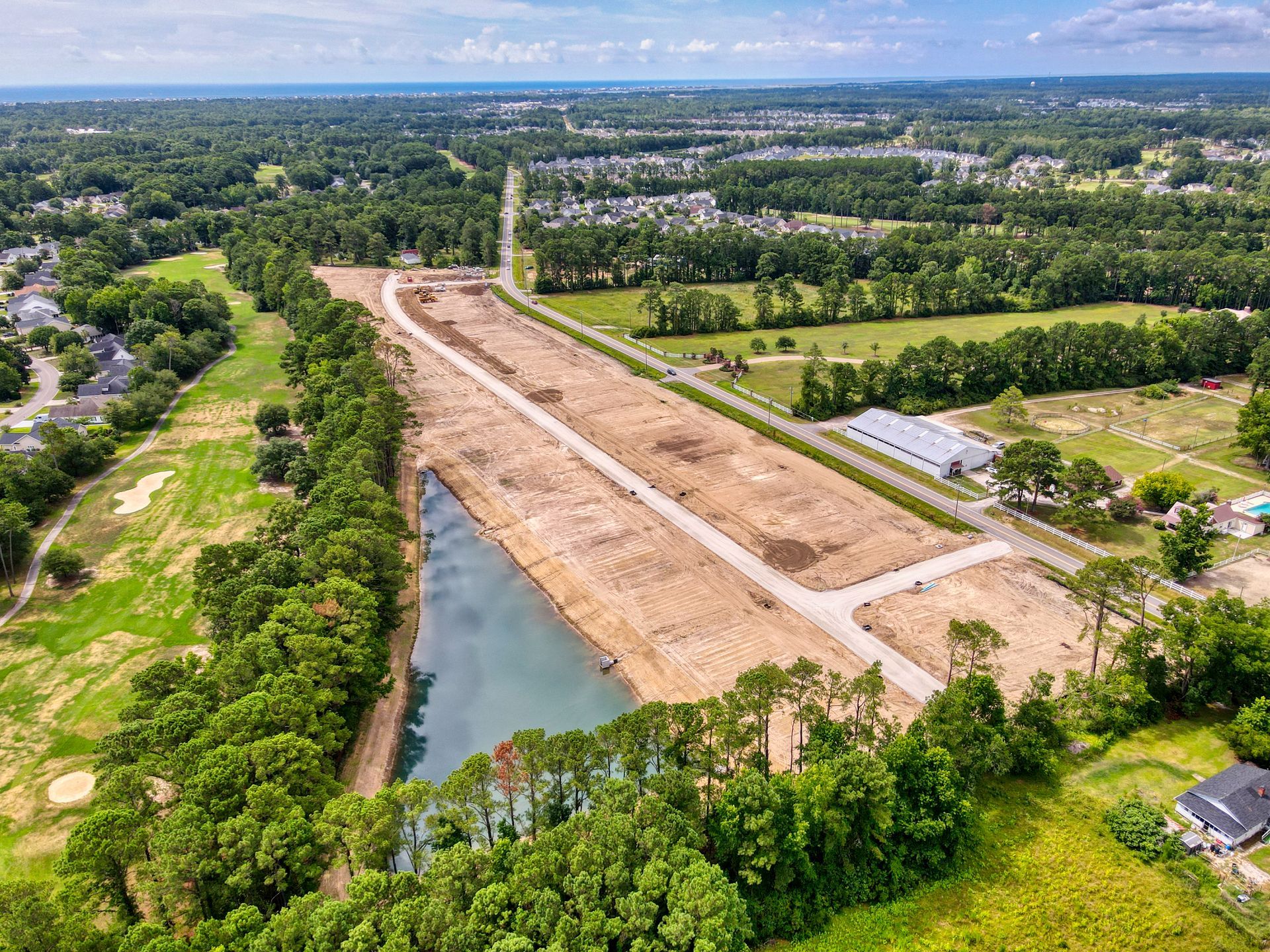 Aerial view of cleared land for development next to a lake and golf course.