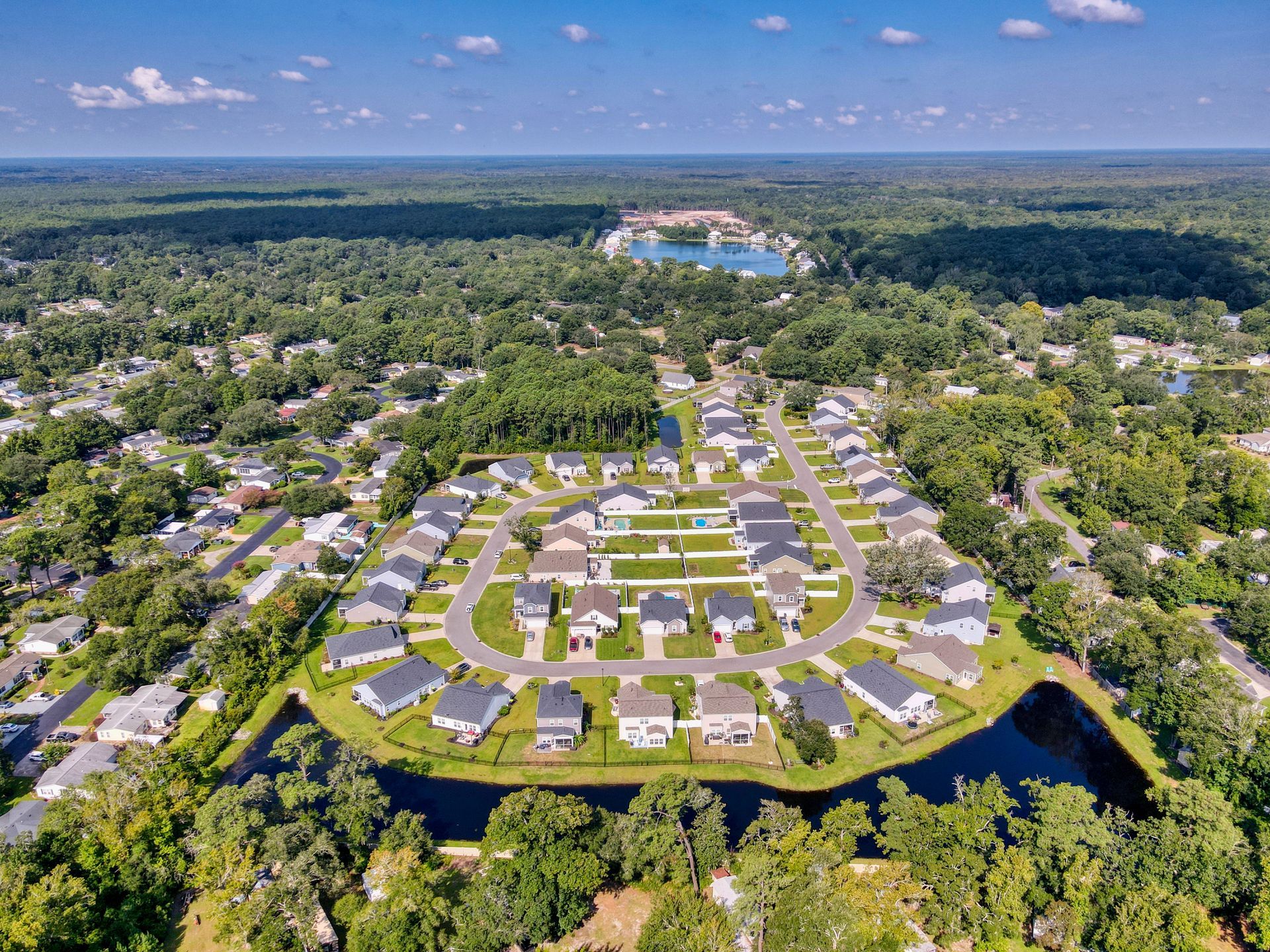 Aerial view of a suburban neighborhood with houses, streets, and surrounding trees.